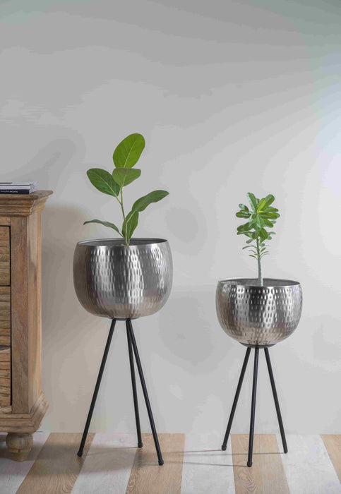 Bring a taste of the green outdoors into the comfort of your own home with just the addition of some fresh plants. Use this modern inspired pot planter to grow your favorite flower, cactus, herb and more. It features a geometric stand, that allows this piece to be placed on the ground next to a desk, fireplace, or seating arrangement. The planter itself is crafted from galvanized metal.