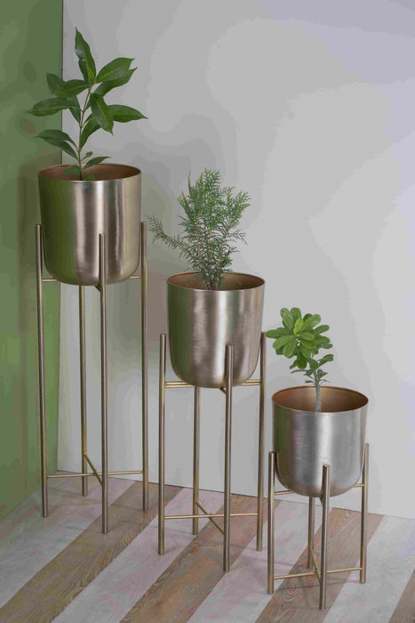 Bring a taste of the green outdoors into the comfort of your own home with just the addition of some fresh plants. Use this modern inspired pot planter to grow your favorite flower, cactus, herb and more. It features a geometric stand, that allows this piece to be placed on the ground next to a desk, fireplace, or seating arrangement. The planter itself is crafted from galvanized metal.