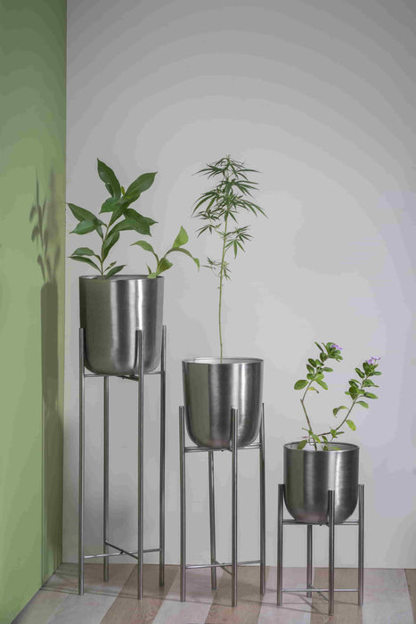 Bring a taste of the green outdoors into the comfort of your own home with just the addition of some fresh plants. Use this modern inspired pot planter to grow your favorite flower, cactus, herb and more. It features a geometric stand, that allows this piece to be placed on the ground next to a desk, fireplace, or seating arrangement. The planter itself is crafted from galvanized metal.