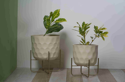 Bring a taste of the green outdoors into the comfort of your own home with just the addition of some fresh plants. Use this modern inspired pot planter to grow your favorite flower, cactus, herb and more. It features a geometric stand, that allows this piece to be placed on the ground next to a desk, fireplace, or seating arrangement. The planter itself is crafted from galvanized metal.