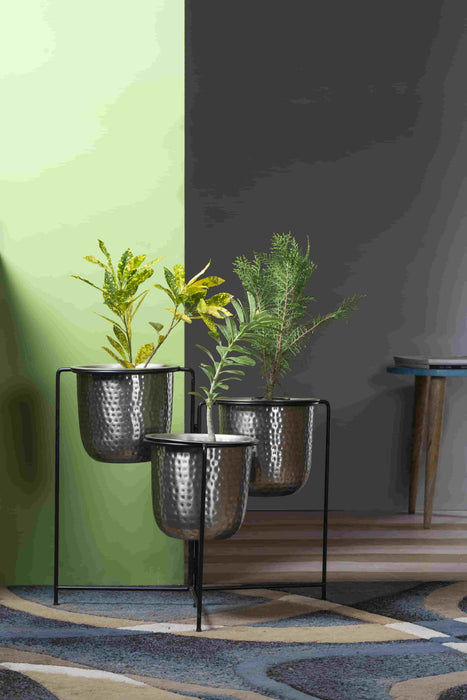 Bring a taste of the green outdoors into the comfort of your own home with just the addition of some fresh plants. Use this modern inspired pot planter to grow your favorite flower, cactus, herb and more. It features a geometric stand, that allows this piece to be placed on the ground next to a desk, fireplace, or seating arrangement. The planter itself is crafted from galvanized metal.